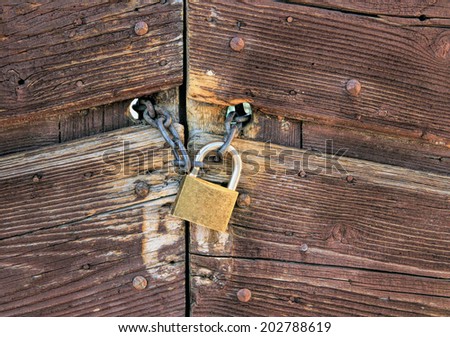 Metallic Padlock on a chain closing a wooden door