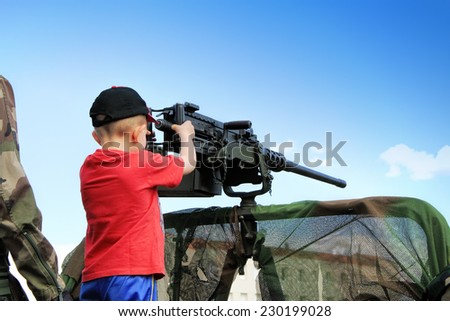 LAUDUN, FRANCE - MAY 01, 2014: Little boy with machine gun during a military show in Laudun, France