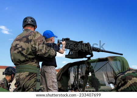 LAUDUN, FRANCE - MAY 01, 2014: Little boy with machine gun during a military show in Laudun, France