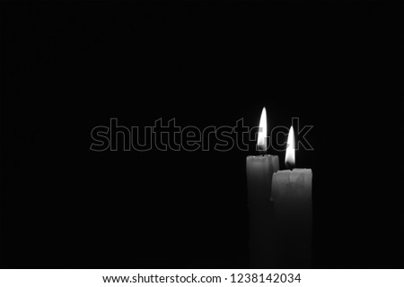 Light candle burning brightly in the black background. Candle flame. There\'s room for your text. Black and white photo. The concept of mourning, grief or sorrow.