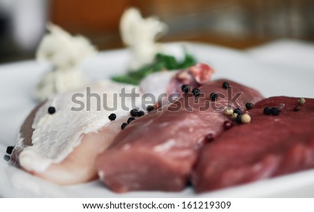 Detail of fresh slices of three types of meat on white plate