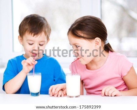 Cute little girl and boy drink tasty fresh milk