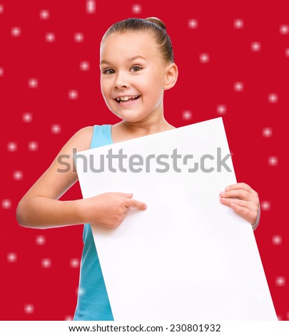 Cute girl is holding blank banner, over red snowy background