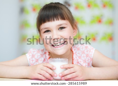Cute happy girl with a glass of milk