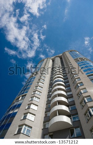 Tall office or residential building on blue sky with clouds. Wide-angle lens used.