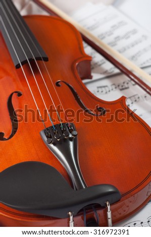 Old violin lying on the sheet of music, music concept.