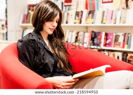 Young woman reading books in a bookstore