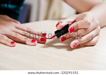 Female carefully painting her fingernails.
