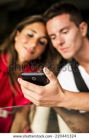 Beautiful Couple looking pics on mobile phone.