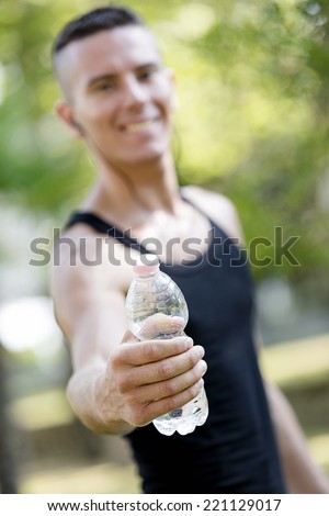 Sweated man takes drink after fitness training in the park.