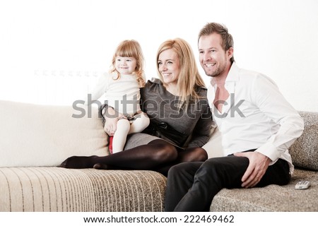 Mother, father and daughter sitting on the sofa.