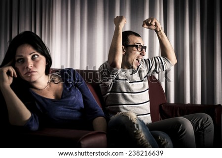 Man watching sports and woman bored. Conflict about the tv program.