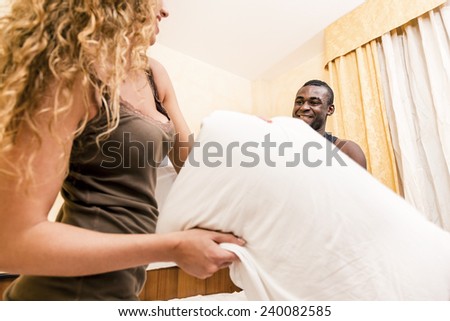 Lovely mixed race couple starting a Pillow fight on bed.