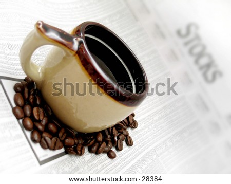 coffee cup and beans sitting on the stocks section of the newspaper.