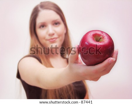 Friendly woman holding apple toward camera.
