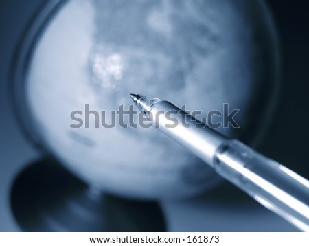Pen tip pointing onto a globe, shallow DOF.