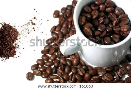 Coffee beans in and around a white mug and ground coffee : Transition.