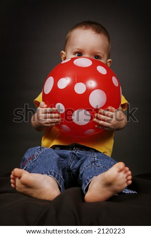Beautiful baby boy hugs his red bouncy ball