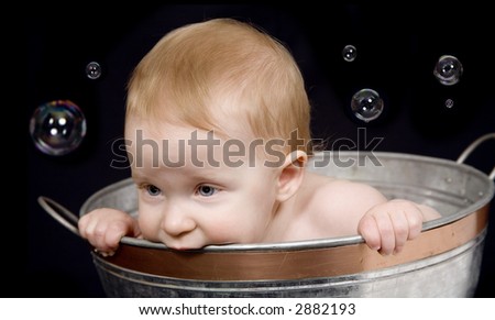 Beautiful one year old baby girl playing with bubbles in a tub