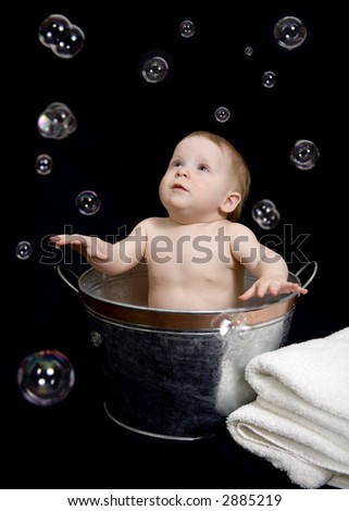 Beautiful one year old baby girl playing with bubbles in a tub