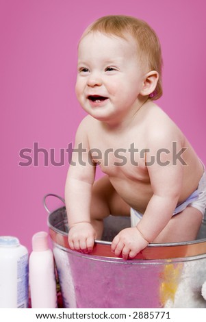 Beautiful one year old baby girl playing in a tub