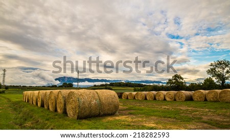 storm is coming on a field with hay bales