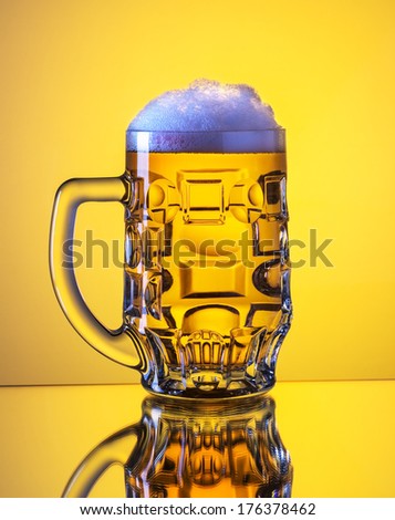 Mug fresh beer with cap of foam isolated over yellow background