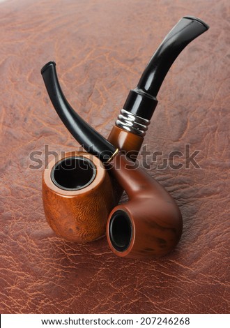 Tobacco pipes on leather background
