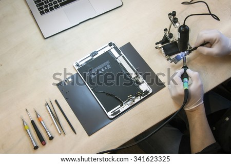 Prague, Czech Republic - NOVEMBER 21, 2014: Photo of the repair process of an iPad Air and iPhone 4. IPad Air and iPhone 4 are produced by Apple Computer, Inc..