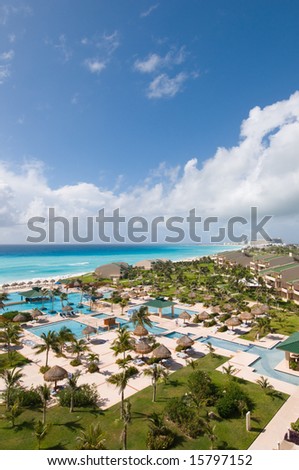 View of luxury tropical oceanfront resort with pools and lush landscaped grounds