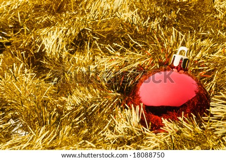Shiny red glass Christmas ball over gold tinsel garland background