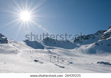T-bar ski lift at high altitude alpine resort, direct sun with flare