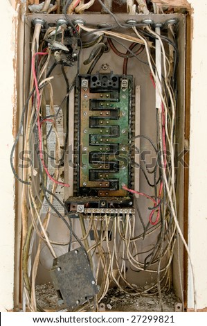 Decaying, broken electrical panel in abandoned building, with exposed wires and breaker switches