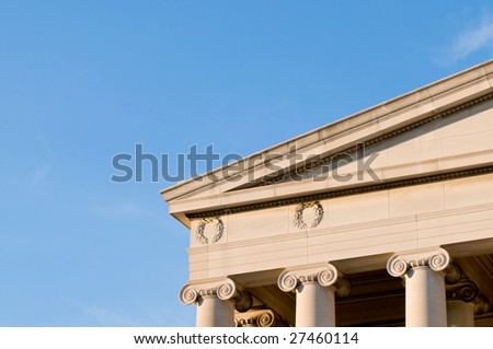 Detail of neoclassical building showing column capitals, cornice and freeze, under warm sunset light