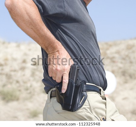 Hand on a handgun about to be pulled from the holster