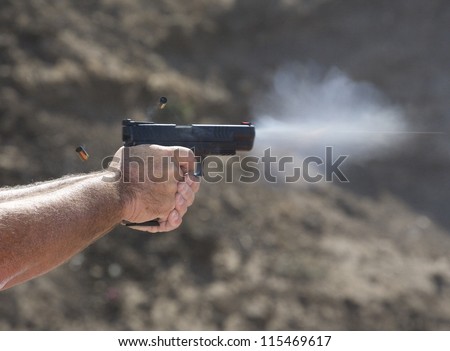 Handgun with empty brass in the air and the bullets vapor trail visible