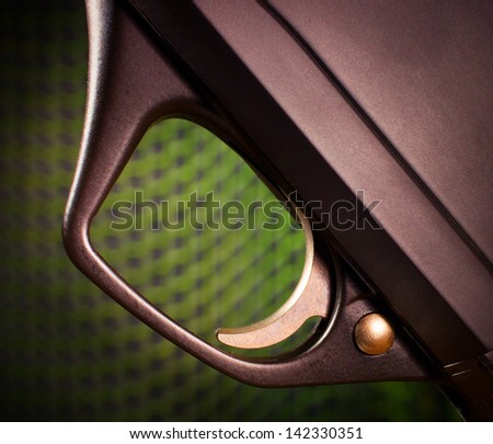 Trigger on a semi automatic shotgun with a green mesh background