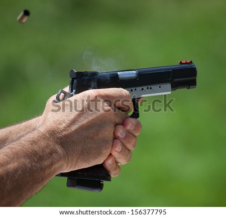 Brass flies away as smoke comes from a semi automatic handgun