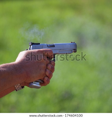 Small puff of smoke coming from a handgun after being fired