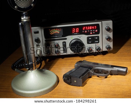 Two way radio and microphone on a table with a gun