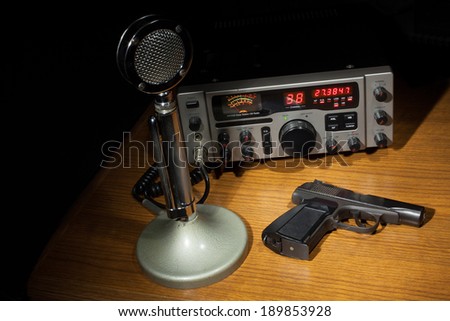 Black handgun on the table with a microphone and two way radio