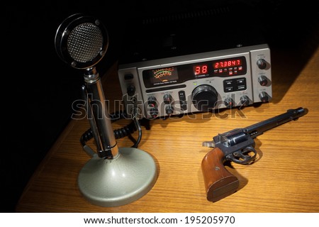 Old microphone and a revolver next to a new two way radio