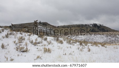 Log cabin in the mountains that is covered in snow