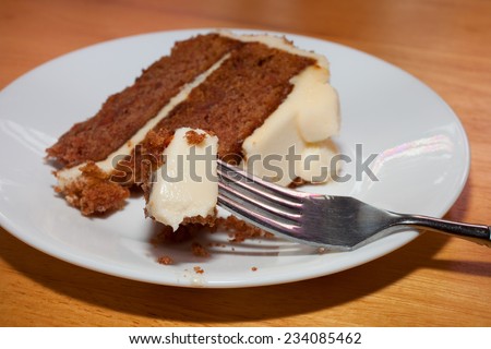 Piece of carrot cake from a slice waiting on a fork
