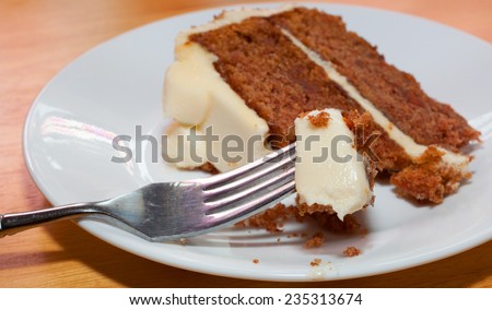 Big piece of carrot cake on a fork with a slice behind