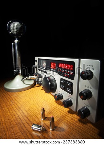 Two way radio and ammunition on a dark desk