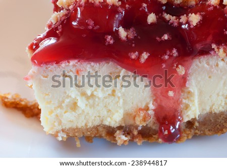 Front of a piece of cheesecake with graham cracker crust and cherry topping