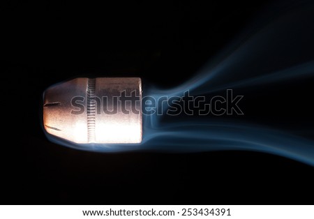 Hollow point handgun bullet with smoke trailing behind