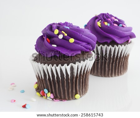 Purple frosted chocolate cupcakes on a white background