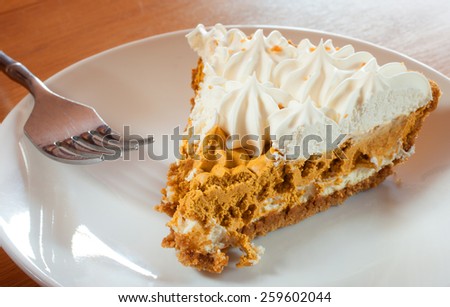Whipped pumpkin pie slice and fork on a white plate